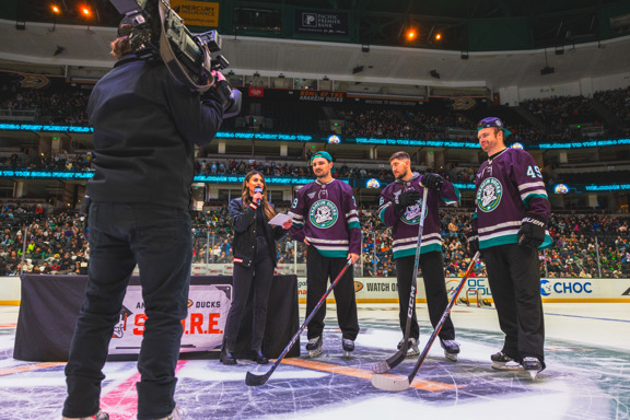 Anaheim Ducks players stand at center ice with the arena host