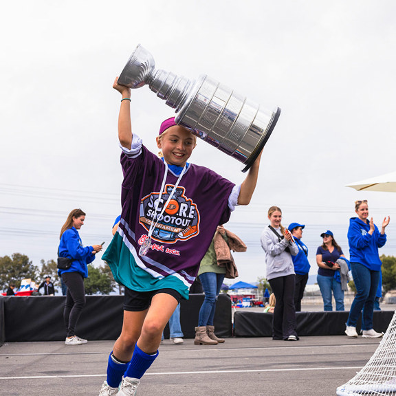 Young girl holds trophy overhead in celebration